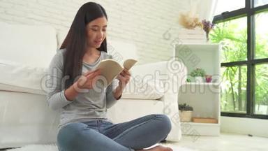 美丽的亚洲女人享受时光，坐在窗前的<strong>现代沙发</strong>上，在客厅看书。